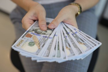 Para elinde, el ele tutuşan dolar banknotları. 
