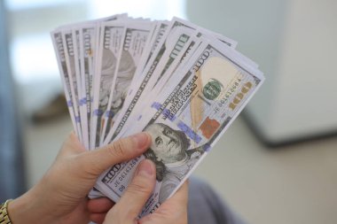 Para elinde, el ele tutuşan dolar banknotları. 