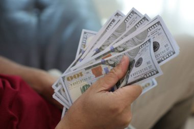 Para elinde, el ele tutuşan dolar banknotları. 
