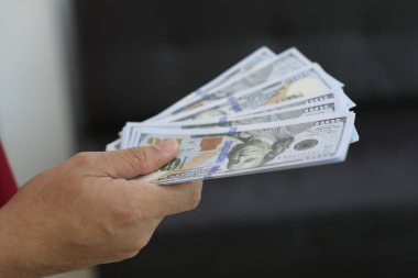 Para elinde, el ele tutuşan dolar banknotları. 