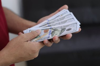 Para elinde, el ele tutuşan dolar banknotları. 