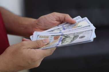 Para elinde, el ele tutuşan dolar banknotları. 