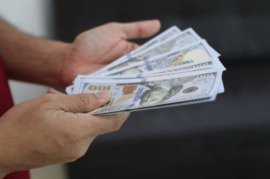Para elinde, el ele tutuşan dolar banknotları. 