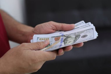 Para elinde, el ele tutuşan dolar banknotları. 