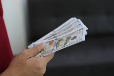 Para elinde, el ele tutuşan dolar banknotları. 