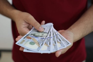 Para elinde, el ele tutuşan dolar banknotları. 