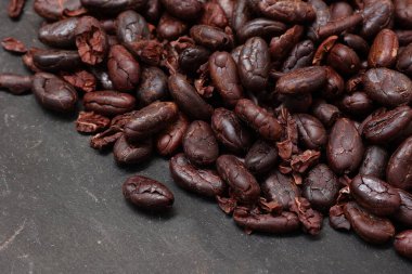 Kahverengi kavrulmuş kakao çekirdeği, siyah arka planda. 