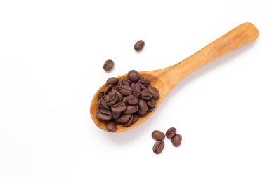 Kahverengi kahve çekirdekleri beyaz arka planda kaşık içinde. 