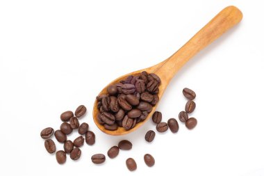 Kahverengi kahve çekirdekleri beyaz arka planda kaşık içinde. 