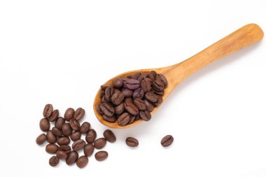 Kahverengi kahve çekirdekleri beyaz arka planda kaşık içinde. 