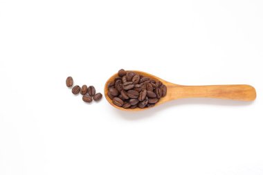 Kahverengi kahve çekirdekleri beyaz arka planda kaşık içinde. 