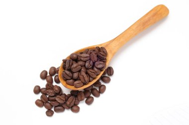 Kahverengi kahve çekirdekleri beyaz arka planda kaşık içinde. 