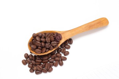 Kahverengi kahve çekirdekleri beyaz arka planda kaşık içinde. 