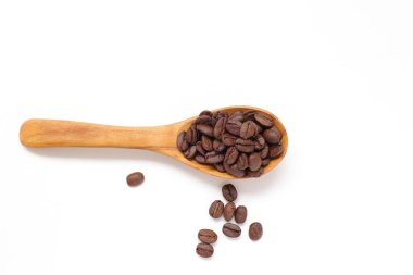 Kahverengi kahve çekirdekleri beyaz arka planda kaşık içinde. 