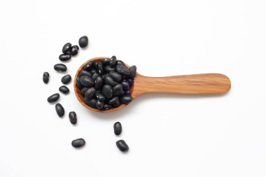 Beyaz arka planda kaşık içinde siyah fasulye tohumları 