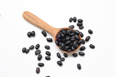 Beyaz arka planda kaşık içinde siyah fasulye tohumları 