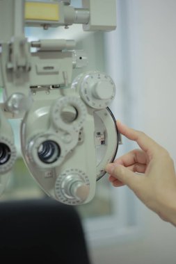 Doktorun elleri tıbbi aletleri çalıştırıyor. Doktorun eli hastanın görme yeteneğini ölçmek için bir makine kullanıyor..