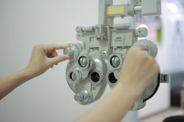 Doktorun elleri tıbbi aletleri çalıştırıyor. Doktorun eli hastanın görme yeteneğini ölçmek için bir makine kullanıyor..