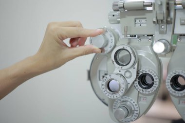 Doktorun elleri tıbbi aletleri çalıştırıyor. Doktorun eli hastanın görme yeteneğini ölçmek için bir makine kullanıyor..