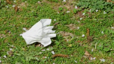 El, çimenlerden doku kağıdı topluyor. Telif alanı hareketsiz vuruşuyla çevreyi koruyor.