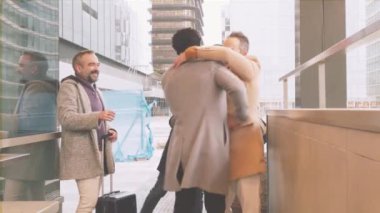 Çeşitli iş ekiplerinin yağmurda tekrar bir araya gelmesi. Gülümsemeler, sarılmalar ve bagaj detayları. Biri kırmızı kulaklıklı, diğeri de güneş gözlüklü. Seyahat, takım çalışması ve başarı temaları için ideal.