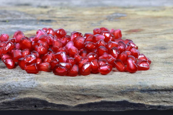 Red Pomegranate seeds on the wooden background. Fresh pomegranate close up picture on the wooden background. Healthful natural fruits for cancer patient