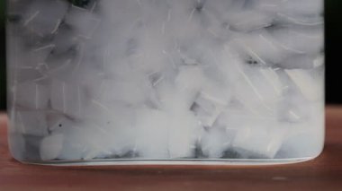 Su şişesinin içinde yüzen aloe vera kesikleri. Suyun içine aloe vera sıçratmanın yavaş hareketi
