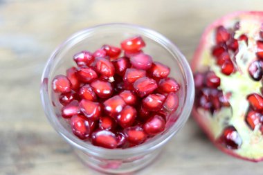 Ahşap arka planda kırmızı nar tohumları. Taze nar, ahşap arka planda yakın plan resmi. Kanser hastaları için sağlıklı doğal meyveler. Nar meyvesinin açık bir bölümü olgun kırmızı tohumları ortaya çıkarır.. 