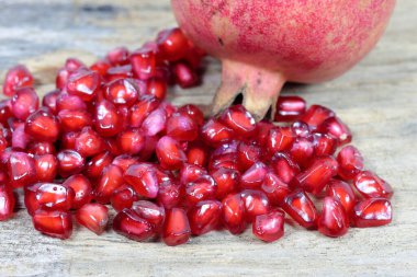 Ahşap arka planda kırmızı nar tohumları. Taze nar, ahşap arka planda yakın plan resmi. Kanser hastaları için sağlıklı doğal meyveler. Nar meyvesinin açık bir bölümü olgun kırmızı tohumları ortaya çıkarır.. 