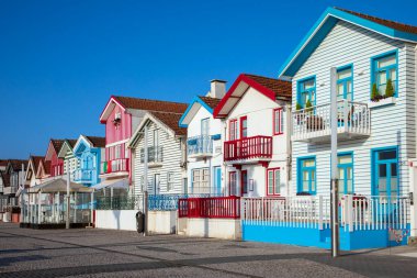 Costa Nova, Portekiz - 21 Haziran 2024: Palheiros adı verilen kırmızı, mavi ve yeşil çizgili renkli çizgili evler