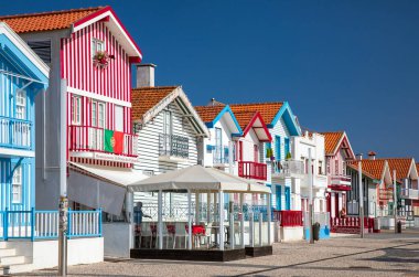 Costa Nova, Portekiz - 21 Haziran 2024: Palheiros adı verilen kırmızı, mavi ve yeşil çizgili renkli çizgili evler