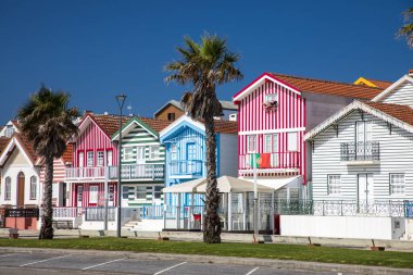 Costa Nova, Portekiz - 21 Haziran 2024: Palheiros adı verilen kırmızı, mavi ve yeşil çizgili renkli çizgili evler