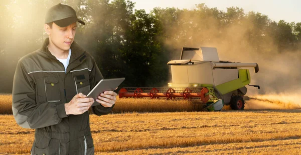 A farmer with digital tablet controls an autonomous harvester on a smart farm