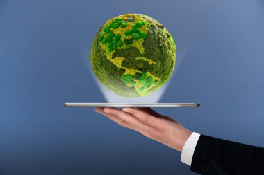 A man is holding a digital tablet. Above this green planet Earth. Symbol of sustainable development and renewable energy  clipart