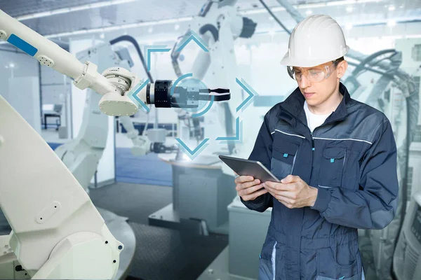 工程师在一个聪明的工厂里使用数字平板来控制机器人 智能工业4 0概念 — 图库照片