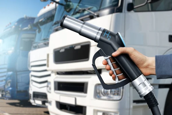 Hand with H2 nozzle on a background of hydrogen fuel cell semi trucks. Eco-friendly commercial vehicle concept