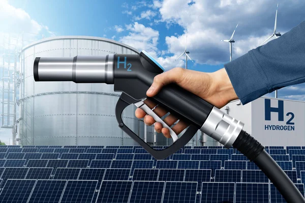 Hand with hydrogen fueling nozzle on a background of H2 factory. Hydrogen production from renewable energy sources concept