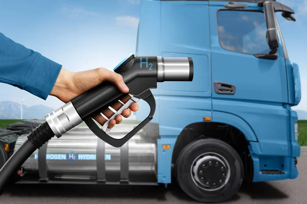 Hand with H2 fueling nozzle on a background of hydrogen fuel cell semi truck with gas tank onboard. Eco-friendly commercial vehicle concept