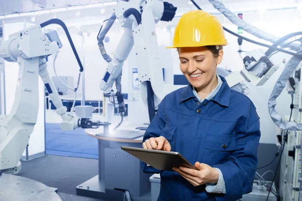 女工程师在一家聪明的工厂里使用数字平板电脑来控制机器人 智能工业4 0概念 — 图库照片