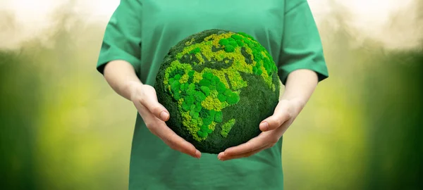 Woman holds a green planet Earth. Symbol of sustainable development and renewable energy