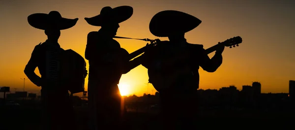 都市のパノラマの背景にメキシコのミュージシャンマリアーチバンドのシルエット — ストック写真