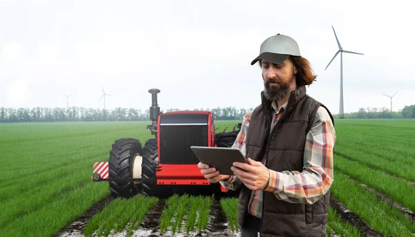 Farmer with digital tablet controls an autonomous tractor on a smart farm