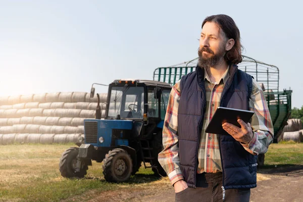 Farmer with a digital tablet on the background of an agricultural tractor. High quality photo