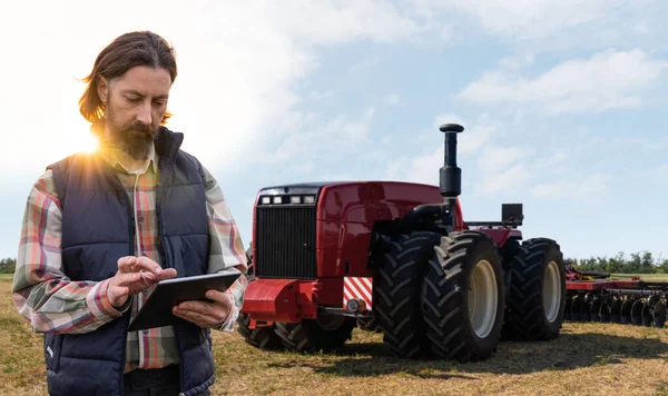 Farmer with digital tablet controls an autonomous tractor on a smart farm. High quality photo