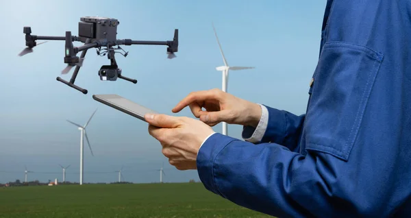 Engineer with tablet computer controls drone on a background of wind turbines. High quality photo