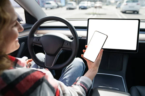 开车的女司机拿着装有白屏的智能手机 高质量的照片 — 图库照片