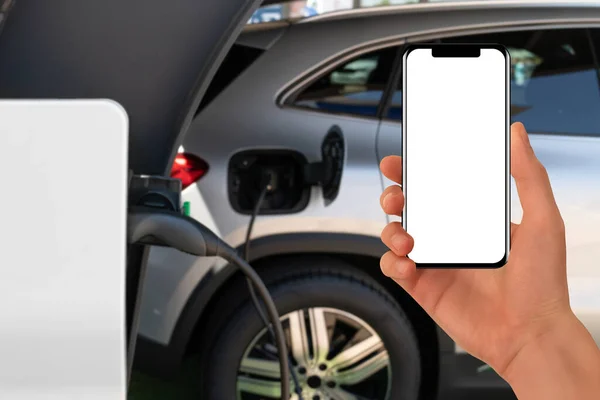 Hand Met Smartphone Een Achtergrond Van Elektrische Auto Wit Scherm — Stockfoto