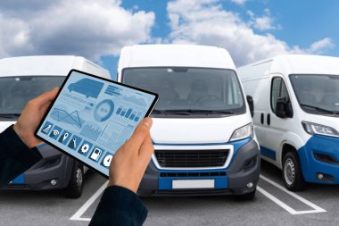Manager with a digital tablet on the background of vans. Fleet management. High quality photo clipart