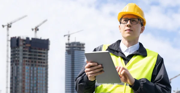 Engineer with a digital tablet on the background of a building under construction. High quality photo
