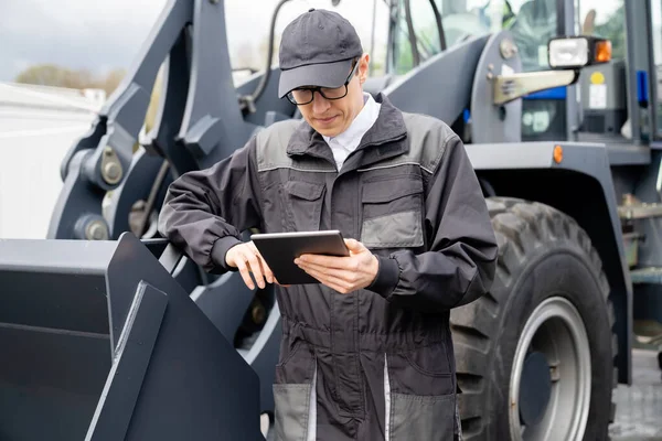 Serviceman Con Tableta Digital Fondo Del Tractor Foto Alta Calidad — Foto de Stock